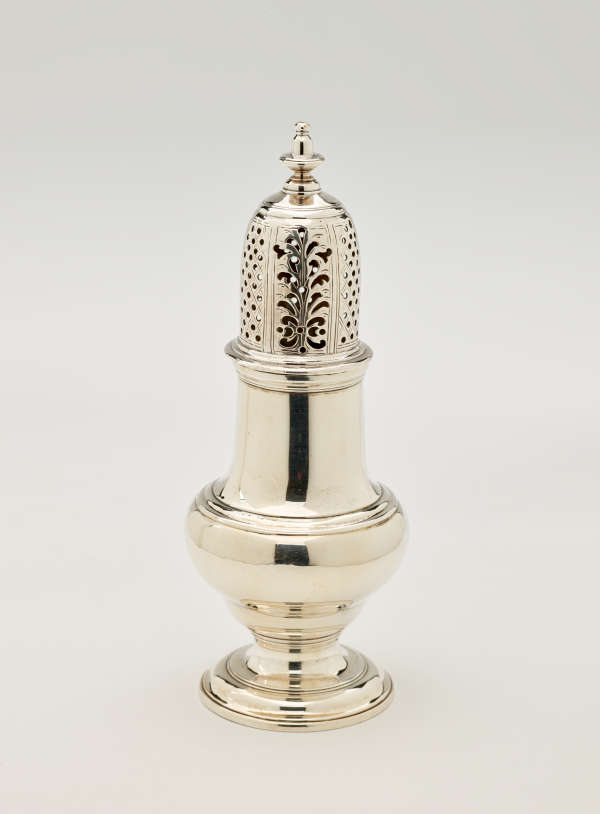 A silver vessel with a foot, rounded body that goes to a cylindrical top half, and the lid is perforated with small holes and floral cutouts.