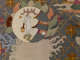 Robe’s back detail. A temple roof framed by clouds is above a golden circle and white bird, and beside a white circle featuring a rabbit, against a dark gridded background.