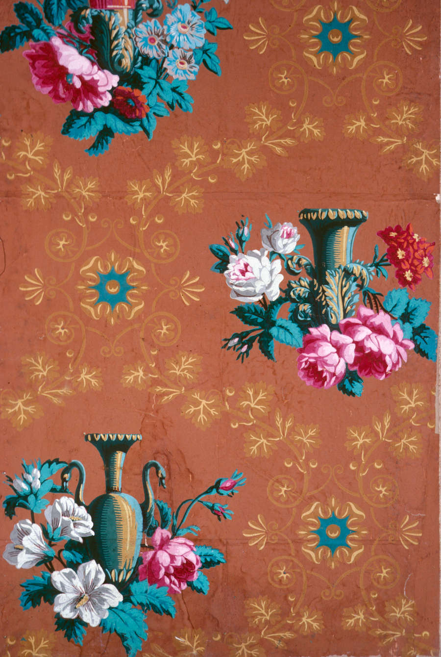 Decorative pattern of various metallic brown vases surrounded by large, vivid blooming flowers set against a warm orange backdrop with subtle teal medallions and gold patterns.