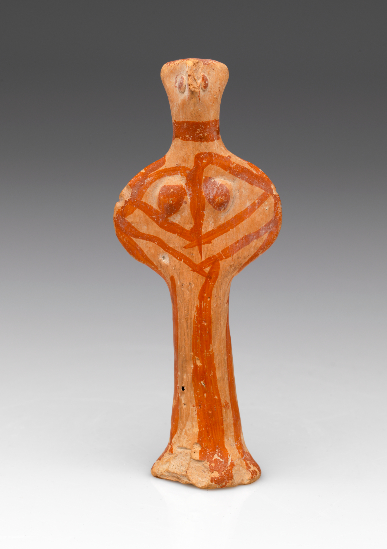 A terracotta figurine with a wide torso, rounded breasts, a narrow base and red painted lines. 