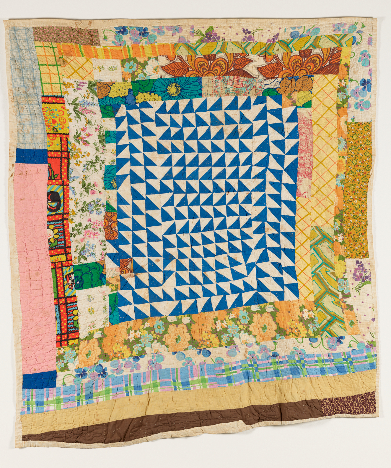 A colorful patchwork quilt with a dense blue and white triangular pattern in the center.