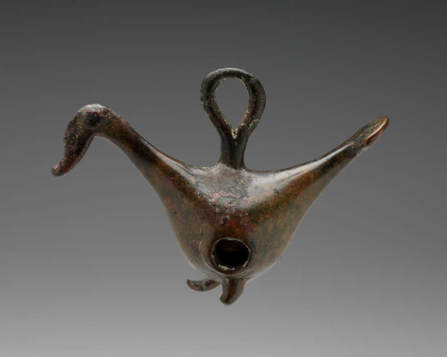 Metal figurine of a bird. A hole goes through the bird’s stomach, and the top of the bird’s back connects to a metal hoop.