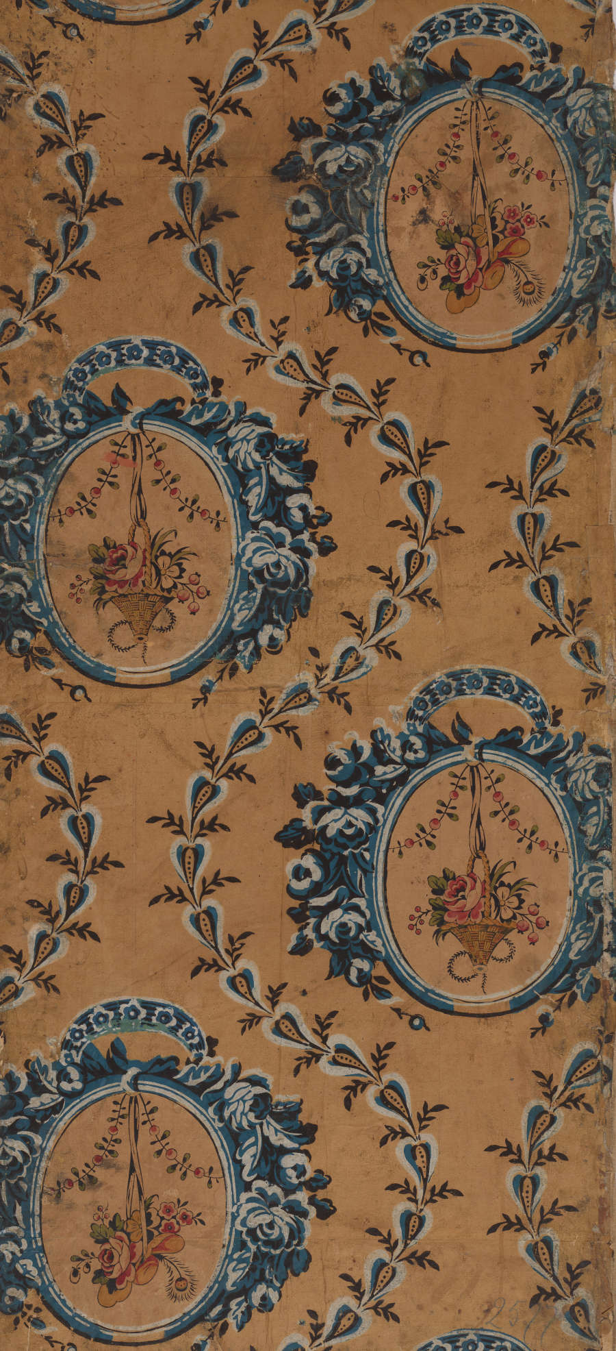 Aged wallpaper containing hanging floral bouquets within blue circular medallions against a pale orange background. Blue vine-like leaves curve around the medallions. 
