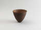 Dark brown ceramic bowl shaped like an inverted cone with a narrow, pointed base, featuring a rough, granular interior surface and a smooth, polished exterior.
