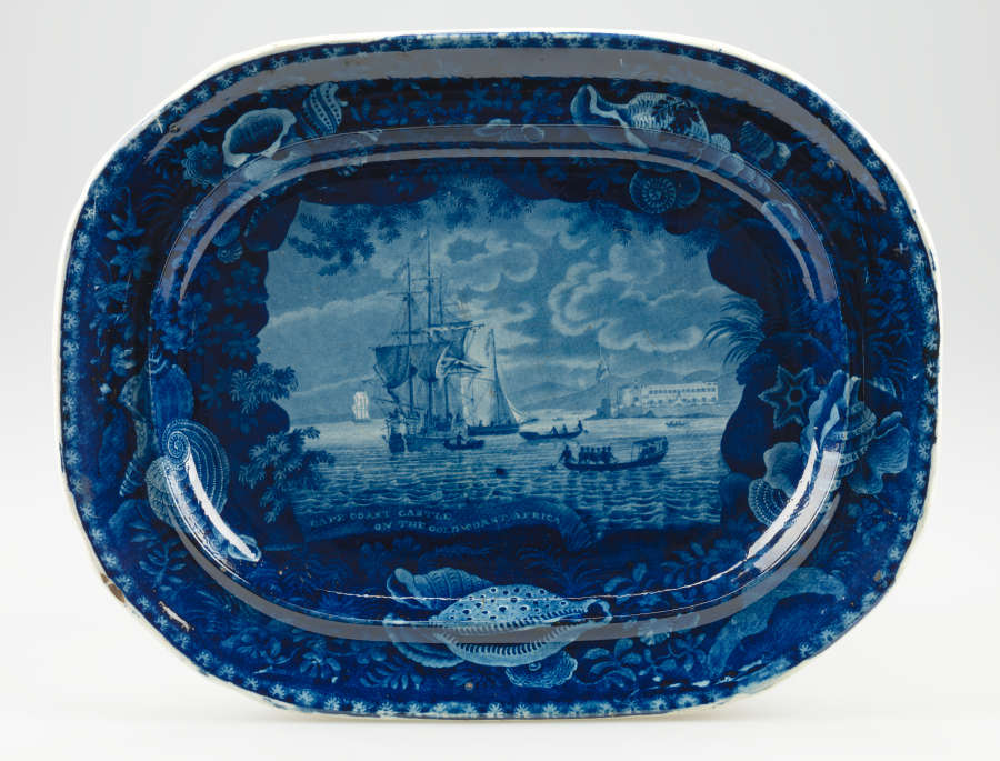 A deep blue ceramic platter with a central illustration of a large ship, framed by a border of seashells, coral, and marine motifs.