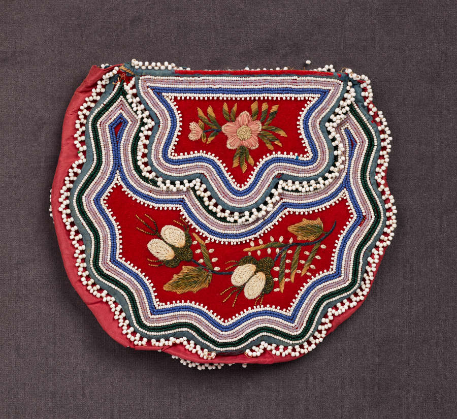 Beaded bag with wavy white, green, blue, and cream stripes framing a red body and top, both of which feature detailed green and white floral embroidery.