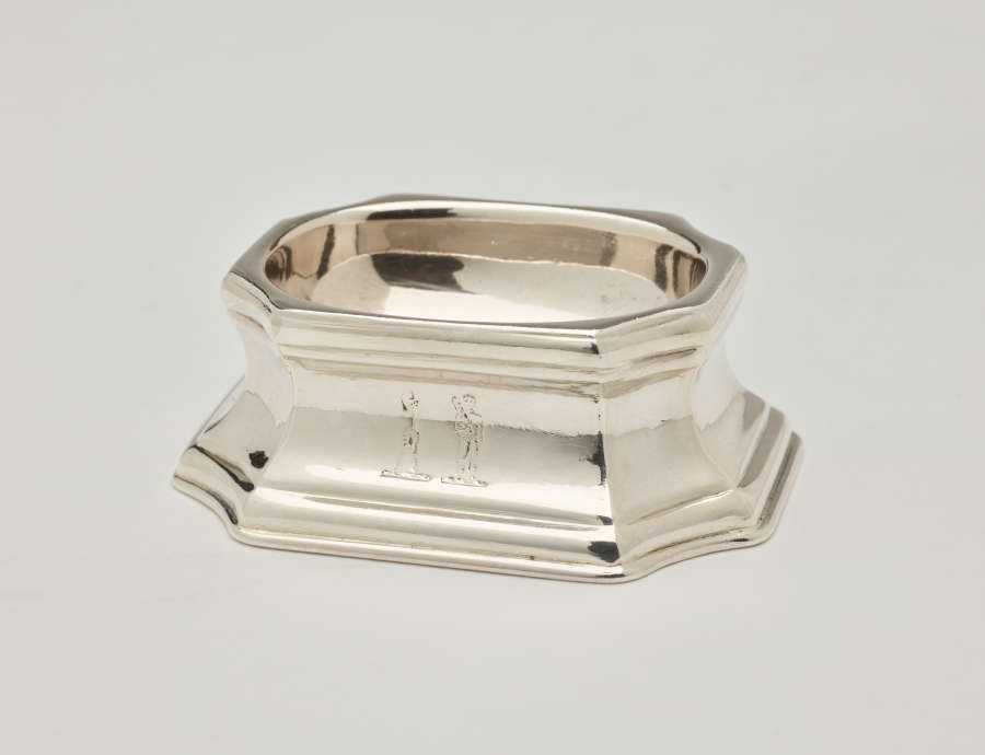 A silver salt container that is rounded on the inside and angular on the outside.
