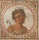 A clay, cream, and green mosaic of a man in a toga wearing a wreath, holding a shepherd’s staff. His portrait is framed by a circle of clay-red swirling patterns.