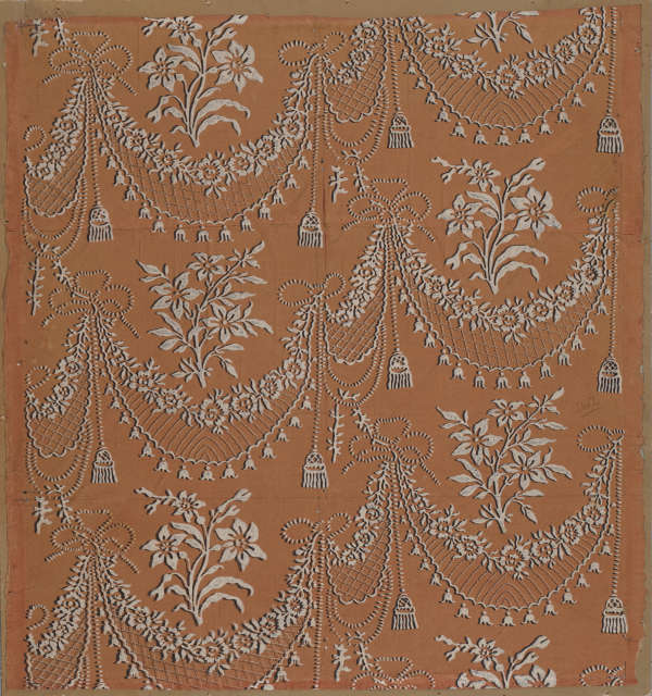 Intricate and elegant patterns of draping florals and tassel motifs done in white appear embossed on a warm dark orange backdrop