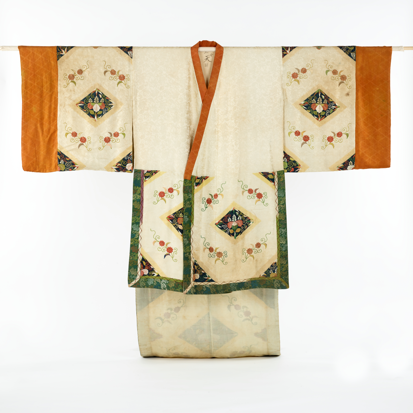 An elegant cream-colored robe with geometric floral embroidery and green trim, contrasted by orange bordered sleeves and neckline.