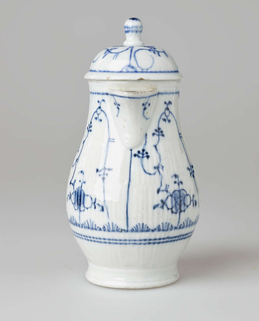 A white chocolate pot with delicate blue decorations with ribbed body, spout, handle, and foot.