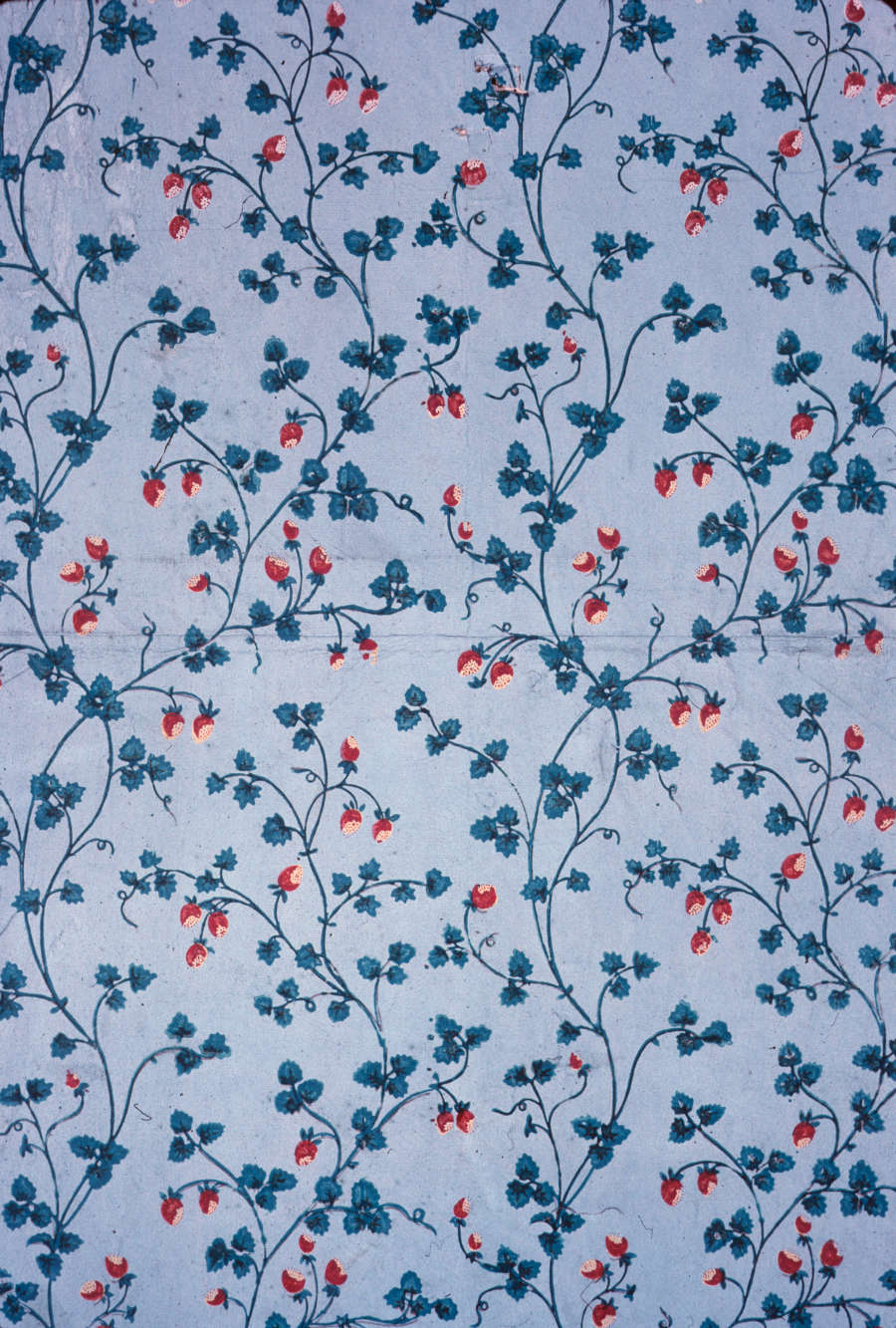 Light blue wallpaper with small, red strawberries and green leaves attached to intertwining green vines throughout.