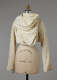 A cream colored, draped garment with wide sleeves and gold-accented scallop designs, fitted on a mannequin torso.