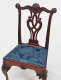 An ornate wooden chair with an intricately carved backrest and a blue floral-patterned fabric seat, with clawed legs.