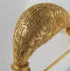 Close-up of the crescent-shaped domed section of the gold pin, adorned with intricate design of animal-like figures and geometric gold patterns made out of tiny gold beading. 