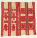 A woven textile of red figures and abstract shapes arranged in vertical bands separated by vertical red bands with multi-colored stripes on a beige cream colored. 