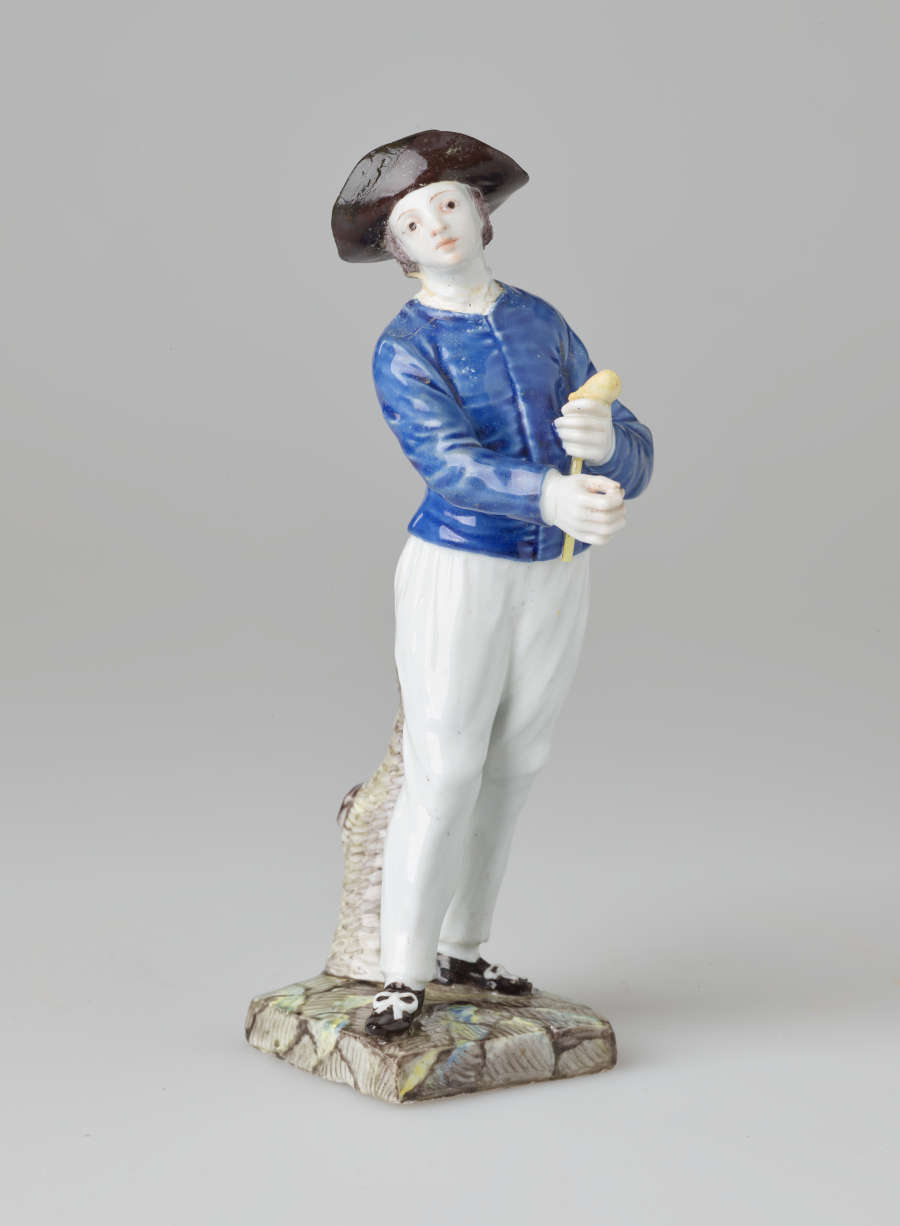 A sculpture of a light-skin figure in historical clothing holding a pipe.
