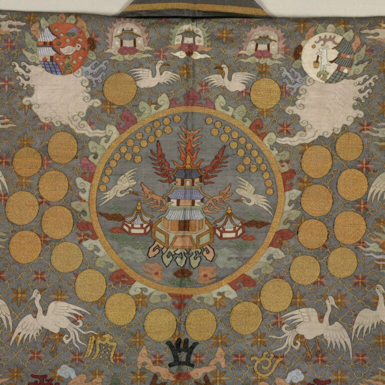 Embroidery covering the back of a gray ceremonial robe, depicting a tiered building inside a gold circle, surrounded by golden disks, flying cranes, and swirling clouds.
