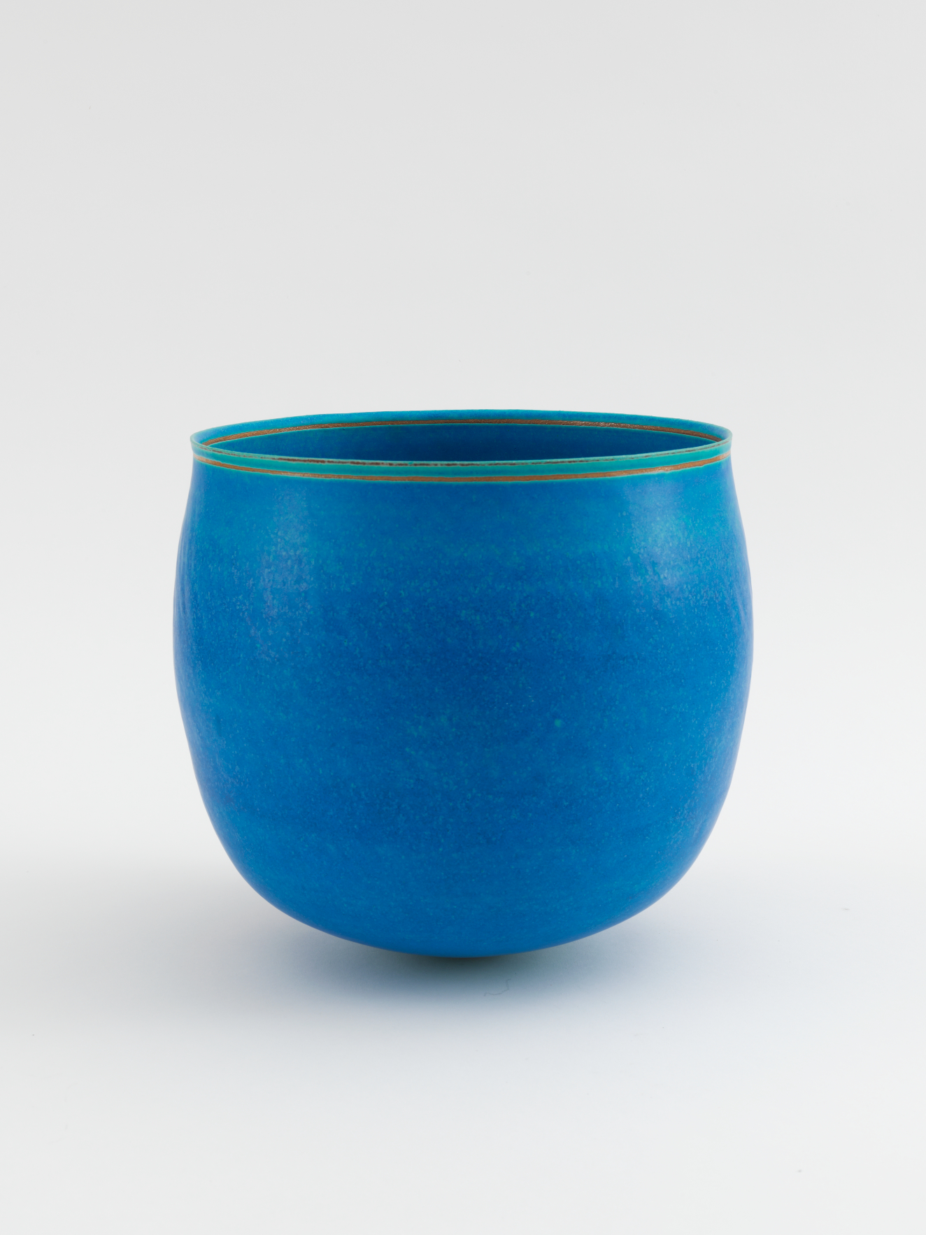 Smooth, rounded ceramic cup with a polished, vivid blue matte surface, its rim neatly accented by a thin green band encircling the opening.