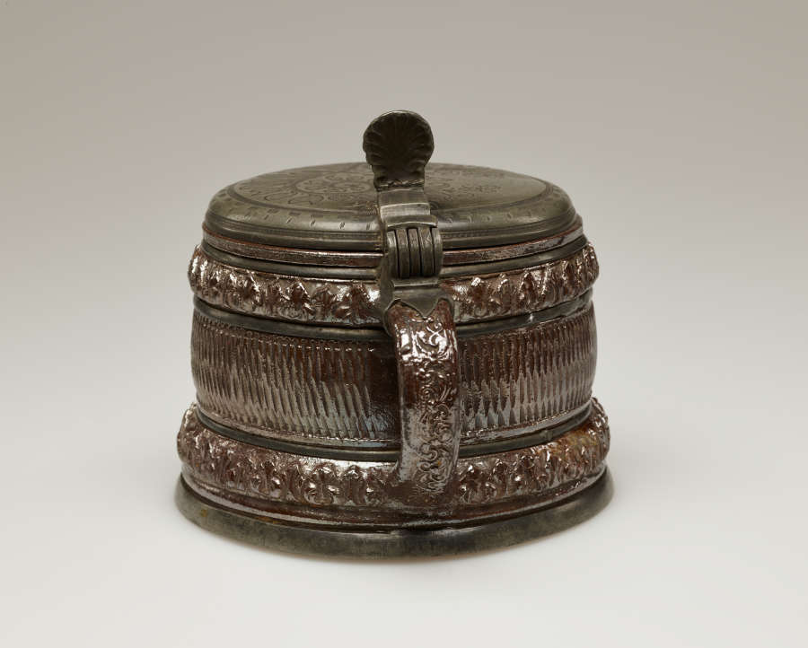 A brown and tan mug with a silver, scalloped rim.