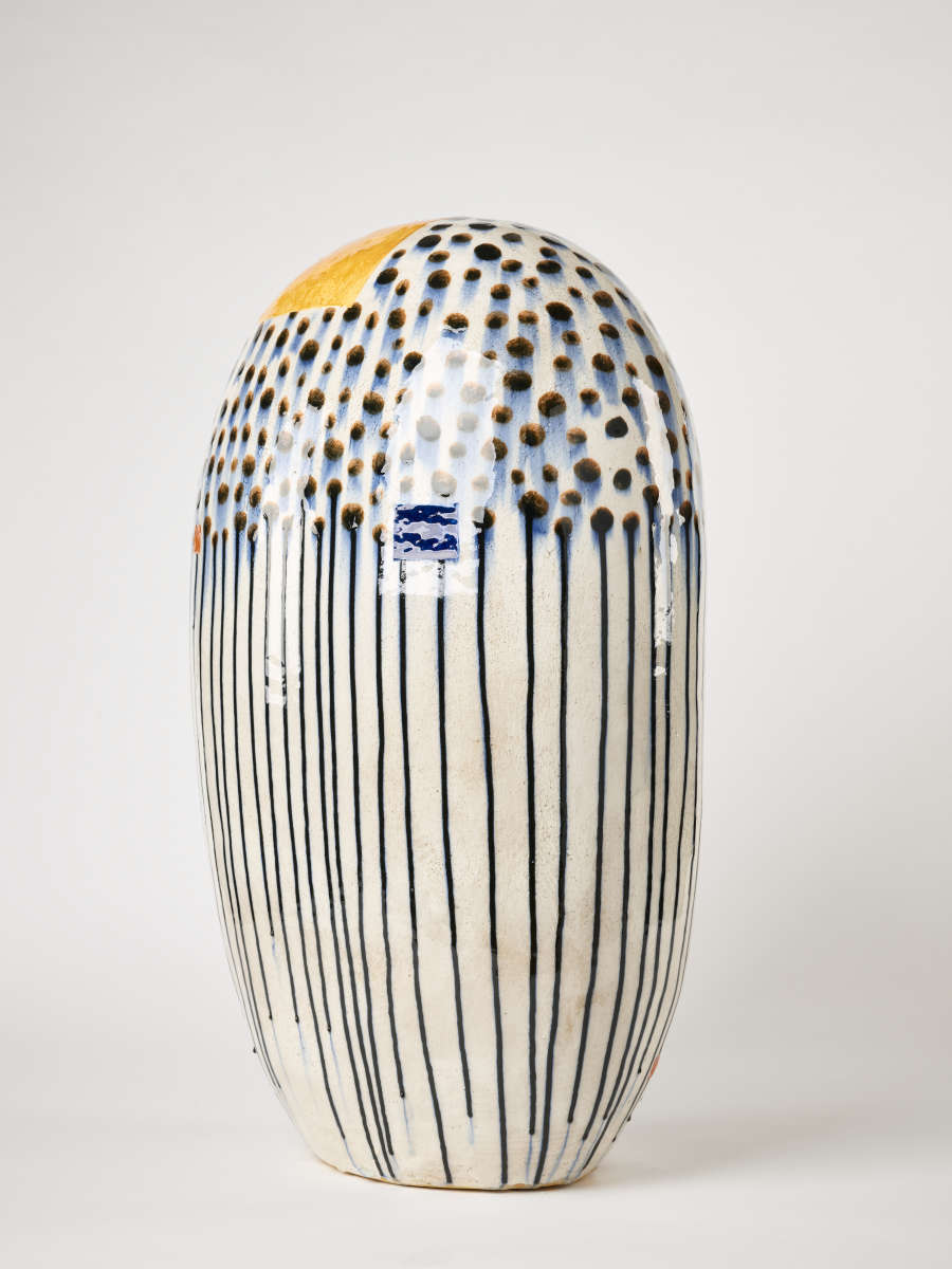 Smooth, elongated white vase with blue dots, partially covered in translucent white squares of paint, descending into lines. The lip is accented with a yellow ochre patch.