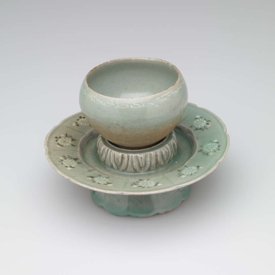 A rounded vessel sitting on a pedestal with a scalloped foot.