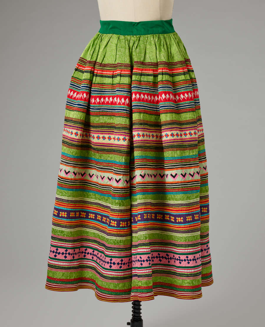 The back view of the green patterned skirt fitted onto a mannequin against a gray background.