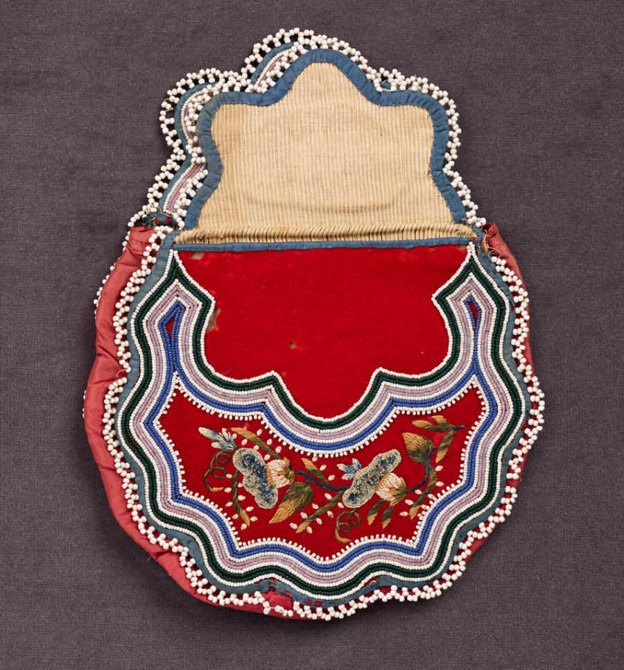Beaded bag with its flap fully open, featuring wavy green, blue, and cream stripes framing a red body and top, both of which feature detailed green and white floral embroidery.