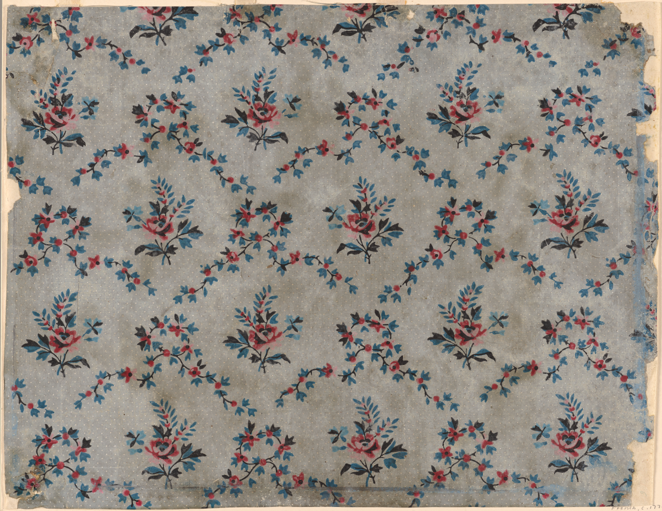 Gray wallpaper with ripped edges, stains, and a repeating floral pattern made out of red and blue flower bouquets surrounded by multiple overlapping red and blue floral garlands.