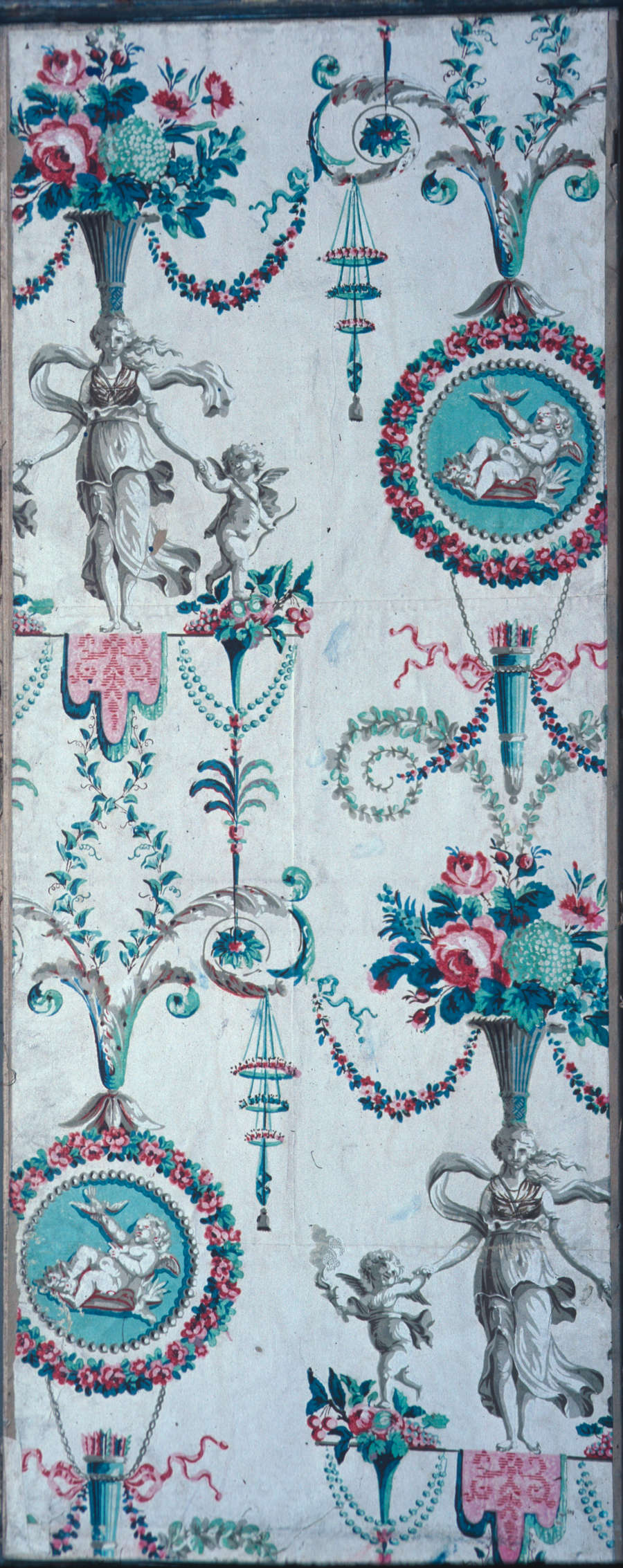 Symmetrical, cream wallcovering featuring colorful floral bouquets, a woman holding two babies in stone, turquoise hanging embellishments, and a laying winged baby within a turquoise medallion and pink floral wreath.